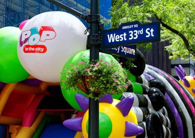 The Pop In The City inflatable next to a West 33rd St Sign