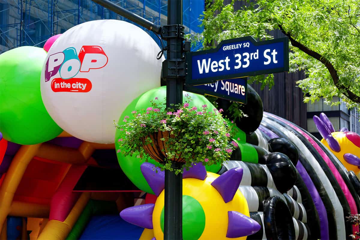 The Pop In The City inflatable next to a West 33rd St Sign